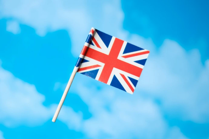 a small british flag flying in the blue sky
